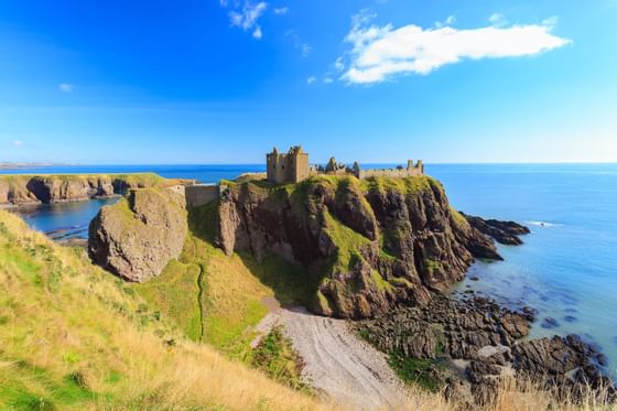 An ancient castle on top of a mountain range facing the sea