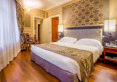 Large bed, comfy pillows & bedside cupboards with lamps in Family Room at Grand Visconti Palace