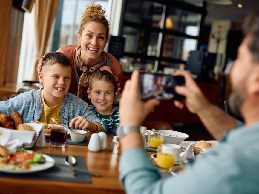 Family smiling at the camera during breakfast with Bed & Breakfast Package offer.