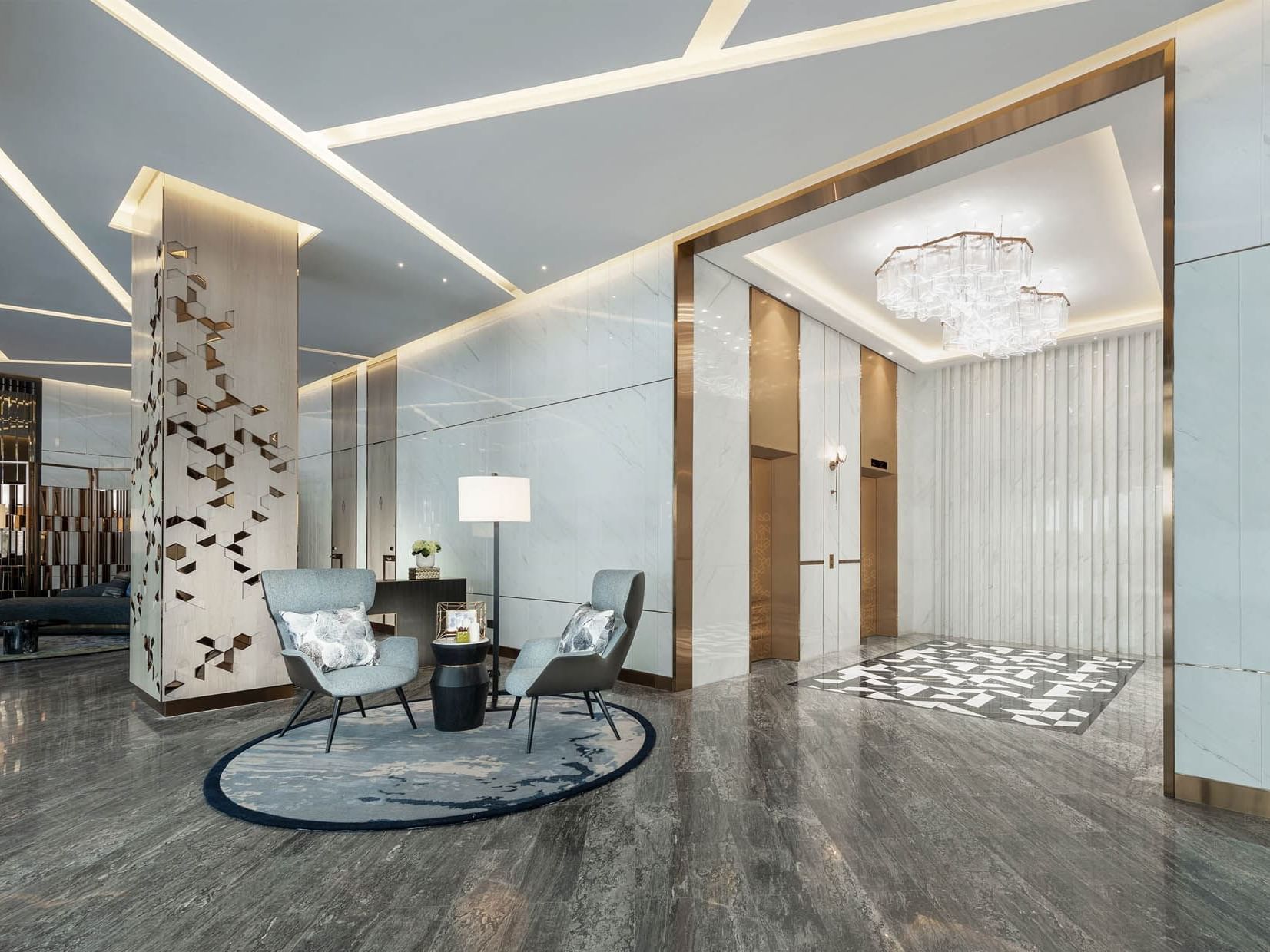 Modern lobby with grey marble floors, stylish chairs, and a decorative wall under a chic chandelier at Orchard Grand Court