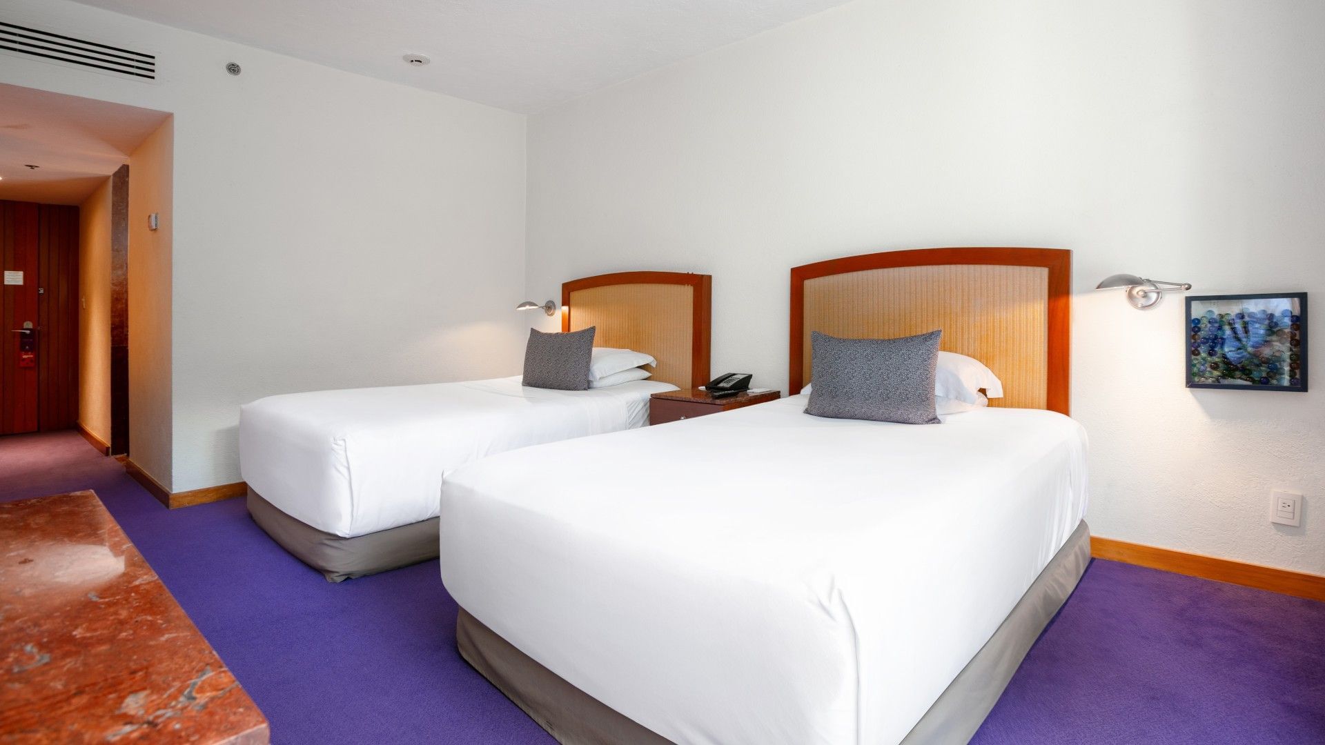2 Double Deluxe room with white linens, wooden headboards, and signature purple rugs at Camino Real Polanco Mexico