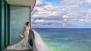 Bride holding a bouquet and gazing at the sea from a balcony at Diplomat Beach Resort