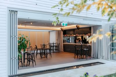 Event Pavilion & Private Dining Room with wooden tables, indoor plants, & a sleek black-tiled bar at Amora Herencia Riverwalk