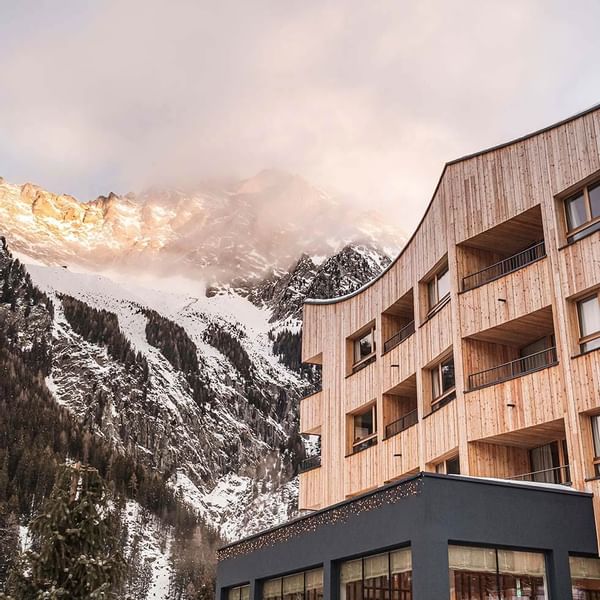 Exxterior view of Falkensteiner Hotel Kronplatz with snowy mountains at the dusk