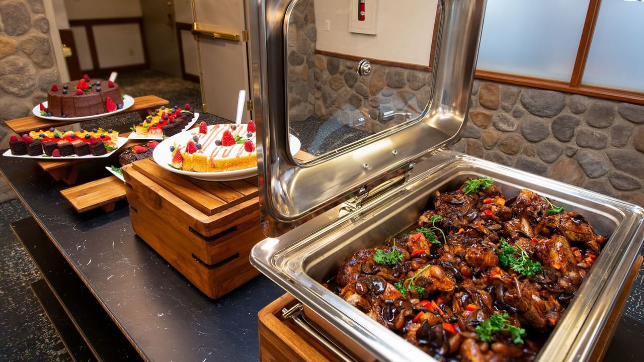 Buffet table with assorted desserts and a dish filled with savory meat.