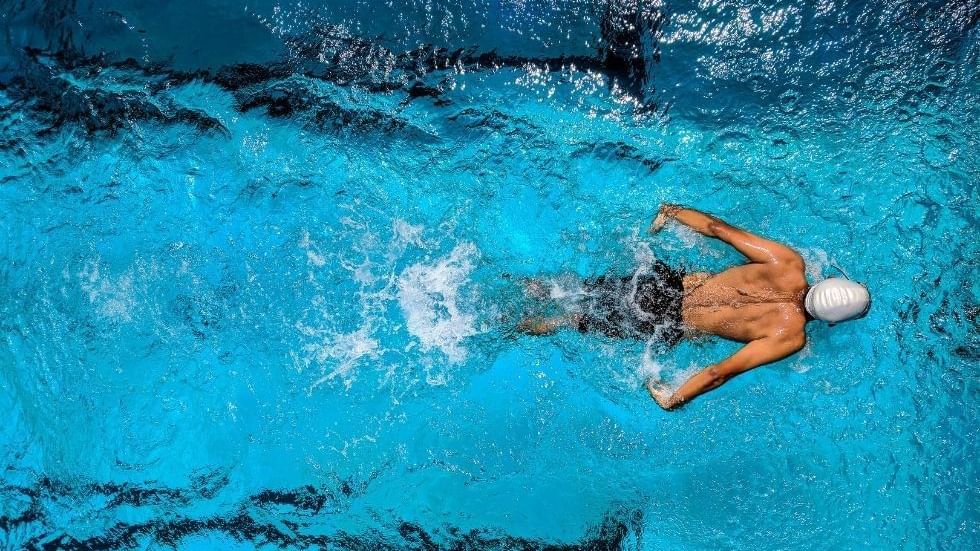 Aerial view of a person swimming in clear blue water & wearing a white cap at Sunway Hotel Big Box