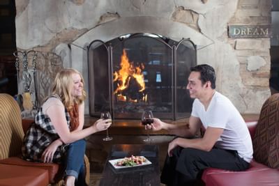 Couple enjoys wine by a fireplace