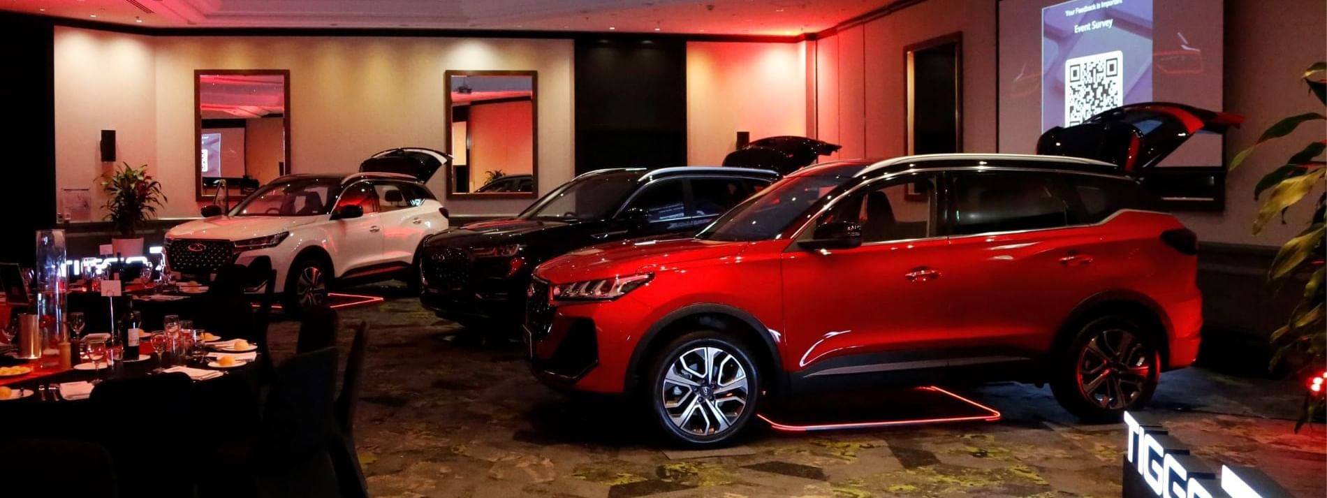 Red SUV and other sleek cars on display beneath ambient lights at Novotel Sydney International Airport