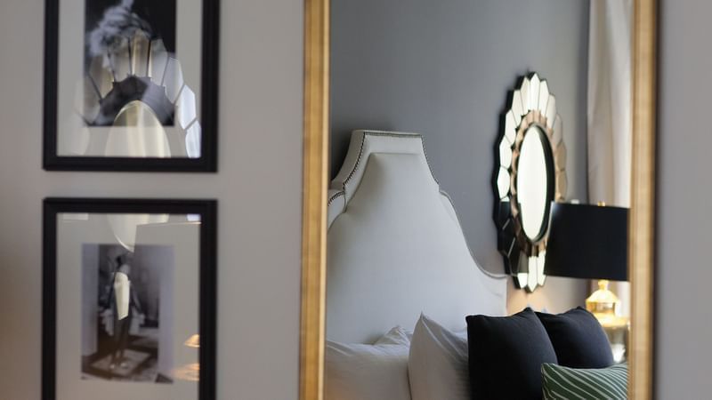Elegant bedroom with white headboard, framed art, and large mirror at Warwick New York.