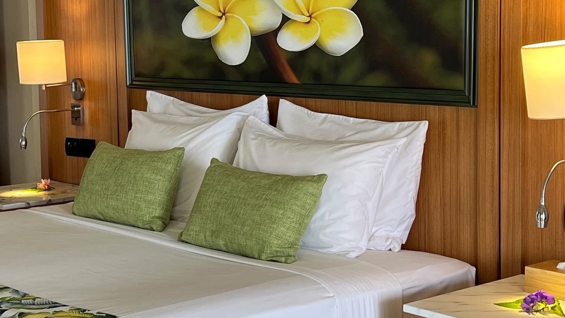 Bed with tropical decor and large floral artwork at Warwick Le Lagon - Vanuatu, Efate.