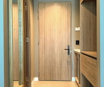 Light wood entrance door beside wardrobe shelving and full-length mirror in a stylish hotel room at Unika Hotels