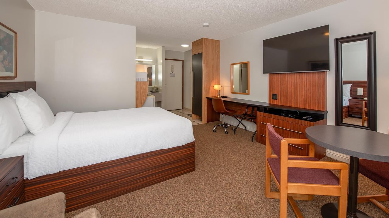 guest room with one queen bed, desk, chair, TV and wood furnishings at Coast Whitecourt Hotel