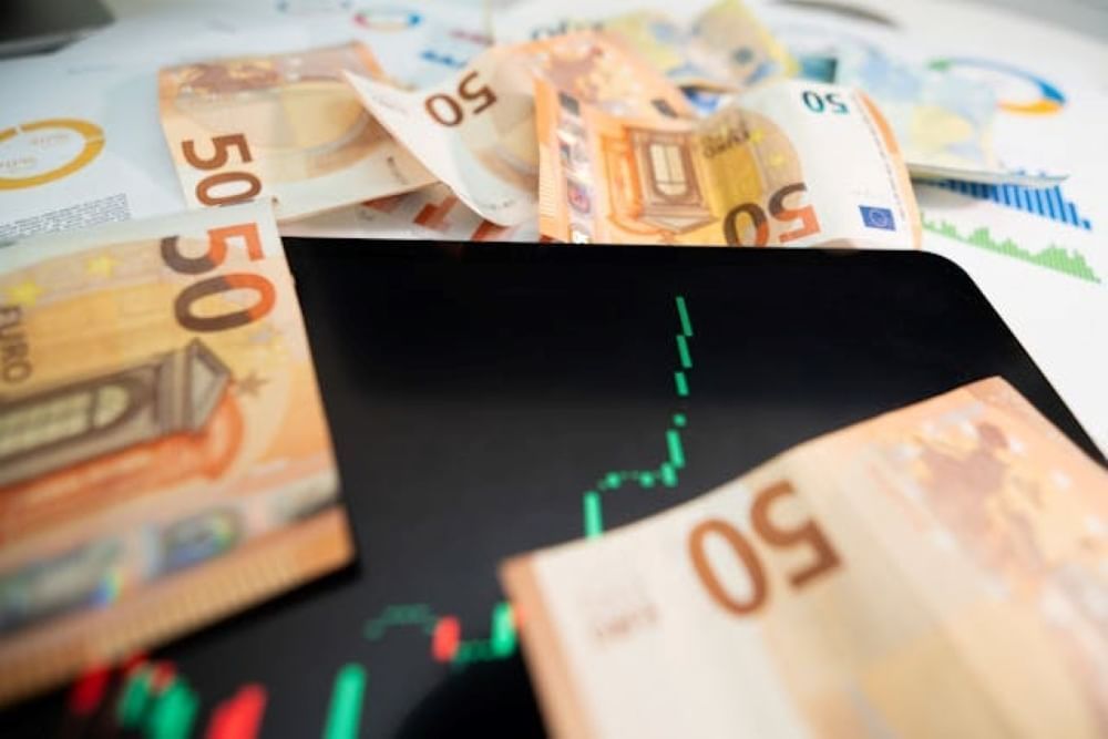 Bills of 50 euros laying on a table and an upward graph with red and green lines.