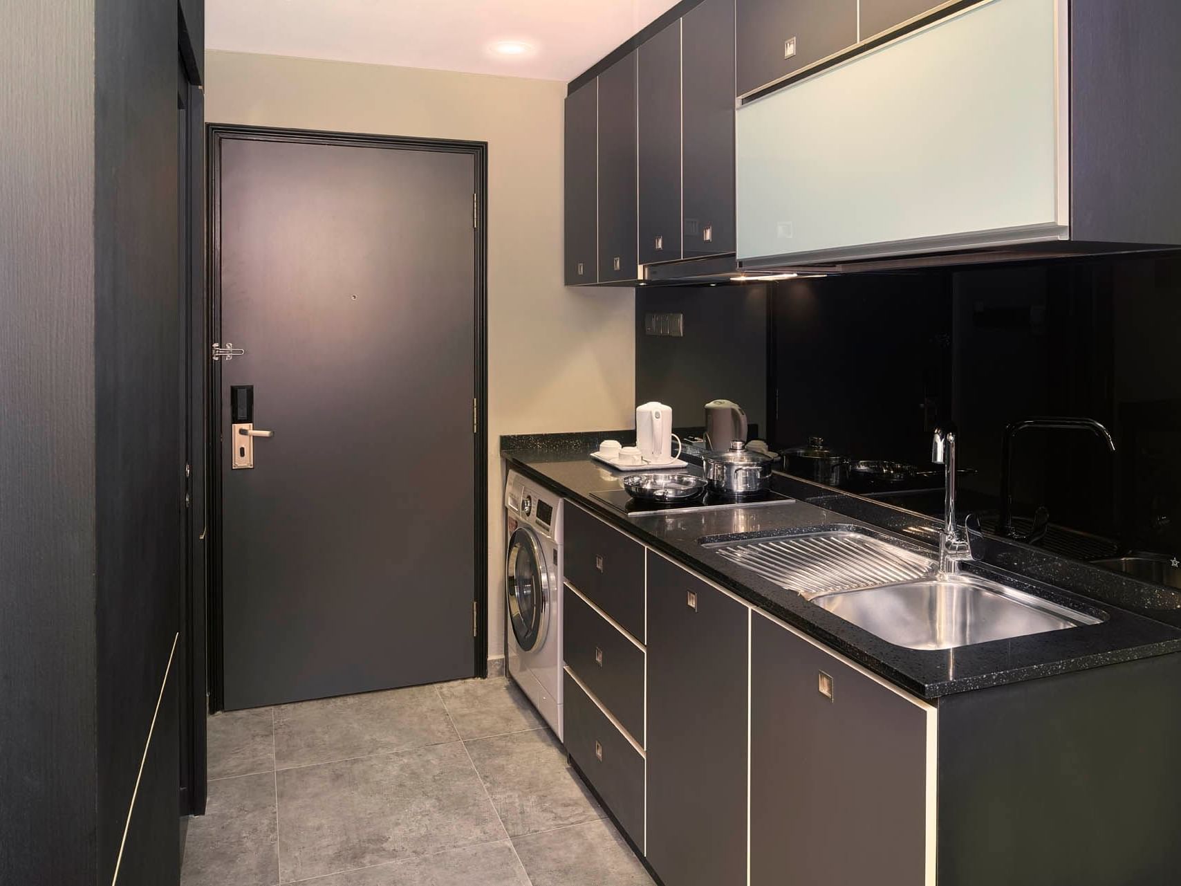 Image 56: Sleek One Bedroom Premier kitchen with dark cabinetry, stainless steel sink, and modern appliances at Orchard Grand Court