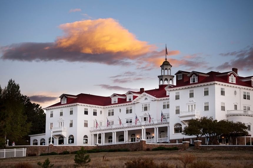 Exterior view of The Stanley Hotel showcasing its grand white structure set against a backdrop of clouds