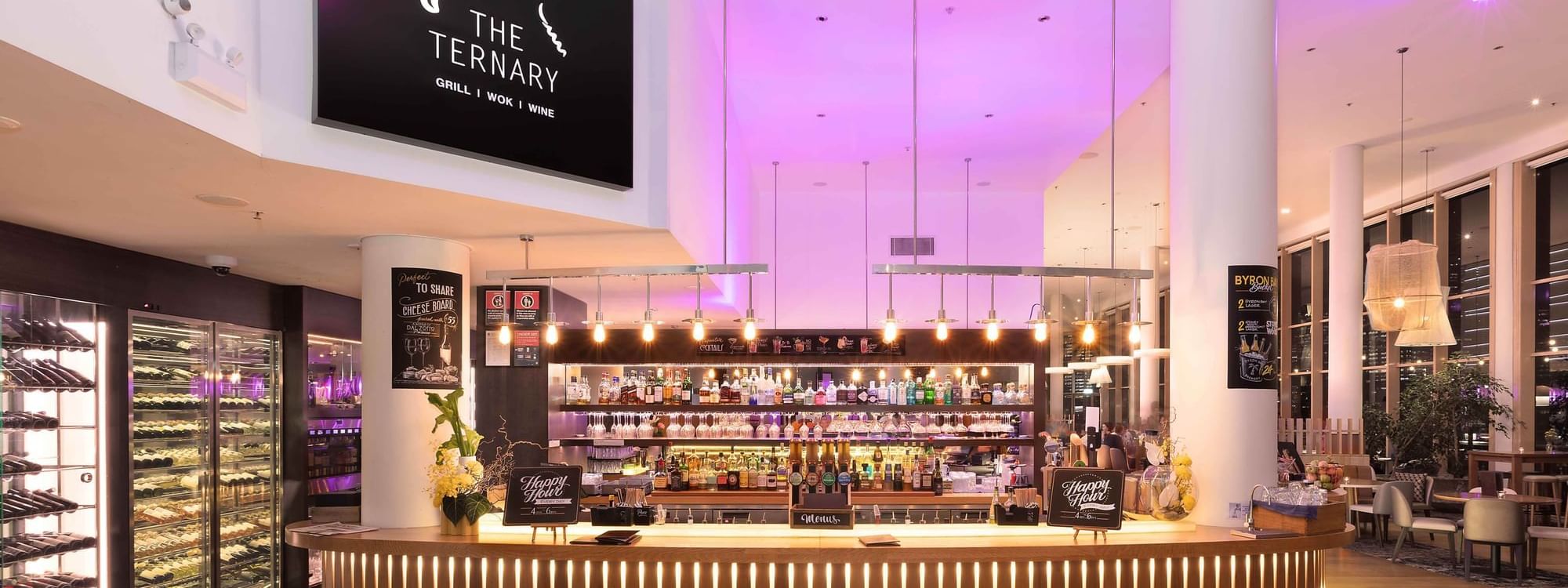 Bar counter with colorful back lighting in the background in The Ternary Bar at Novotel Sydney on Darling Harbour