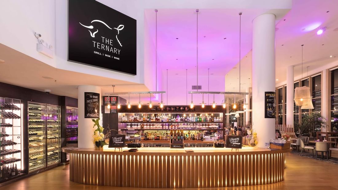 Bar counter with colorful back lighting in the background in The Ternary Bar at Novotel Sydney on Darling Harbour