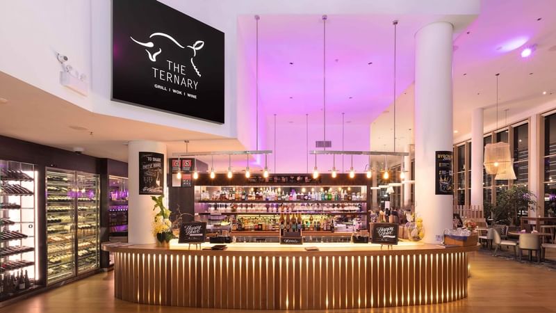 Bar counter with colorful back lighting in the background in The Ternary Bar at Novotel Sydney on Darling Harbour