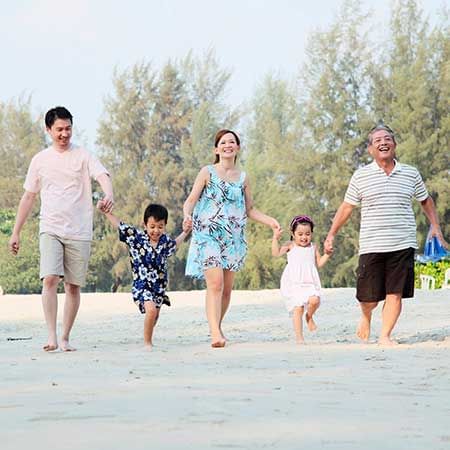 a family holding hands while walking on the beach