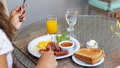 Plate of fried eggs with bacon and baked beans beside crispy toast and orange juice glass at Worthing Court Apartment