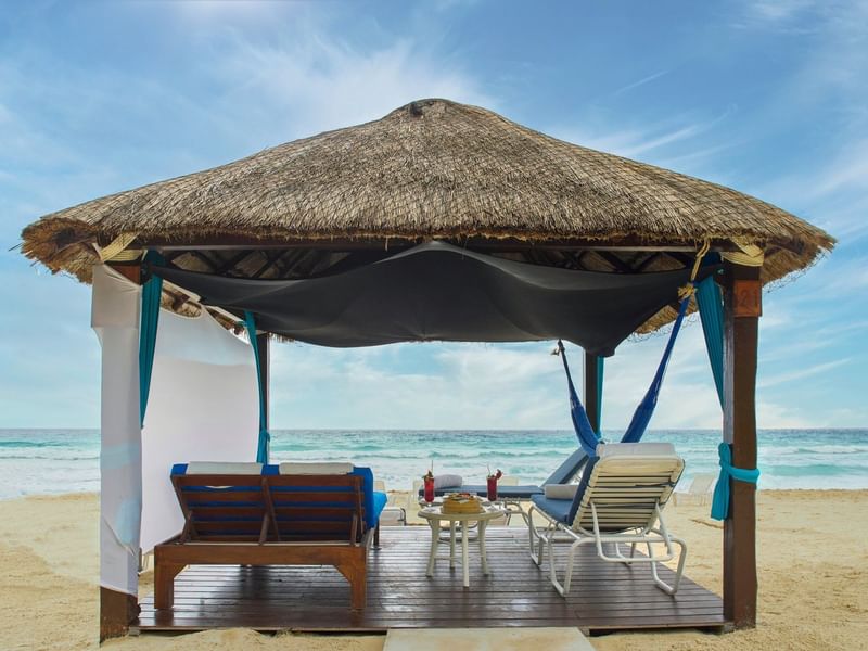 Outdoor dining area with sun loungers by the beach at The Caribe Bar & Grill in Kempinski Hotel Cancún