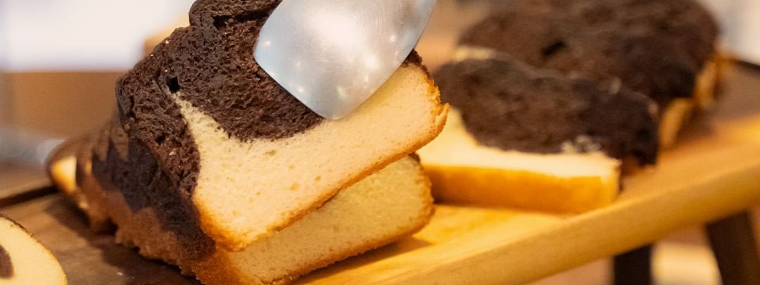 Sliced loaf of marbled chocolate and vanilla cake on a wooden board at Warwick Hotels and Resorts, ready to be served
