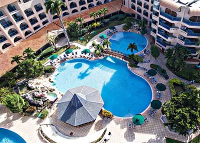 Aerial view of the outdoor pool area with sunbeds and patio umbrellas at Accra Beach Hotel & Spa