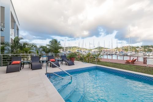 Poolside view with lounge chairs, overlooking a marina filled with boats and lush greenery at Bay Gardens Hotels and Resorts