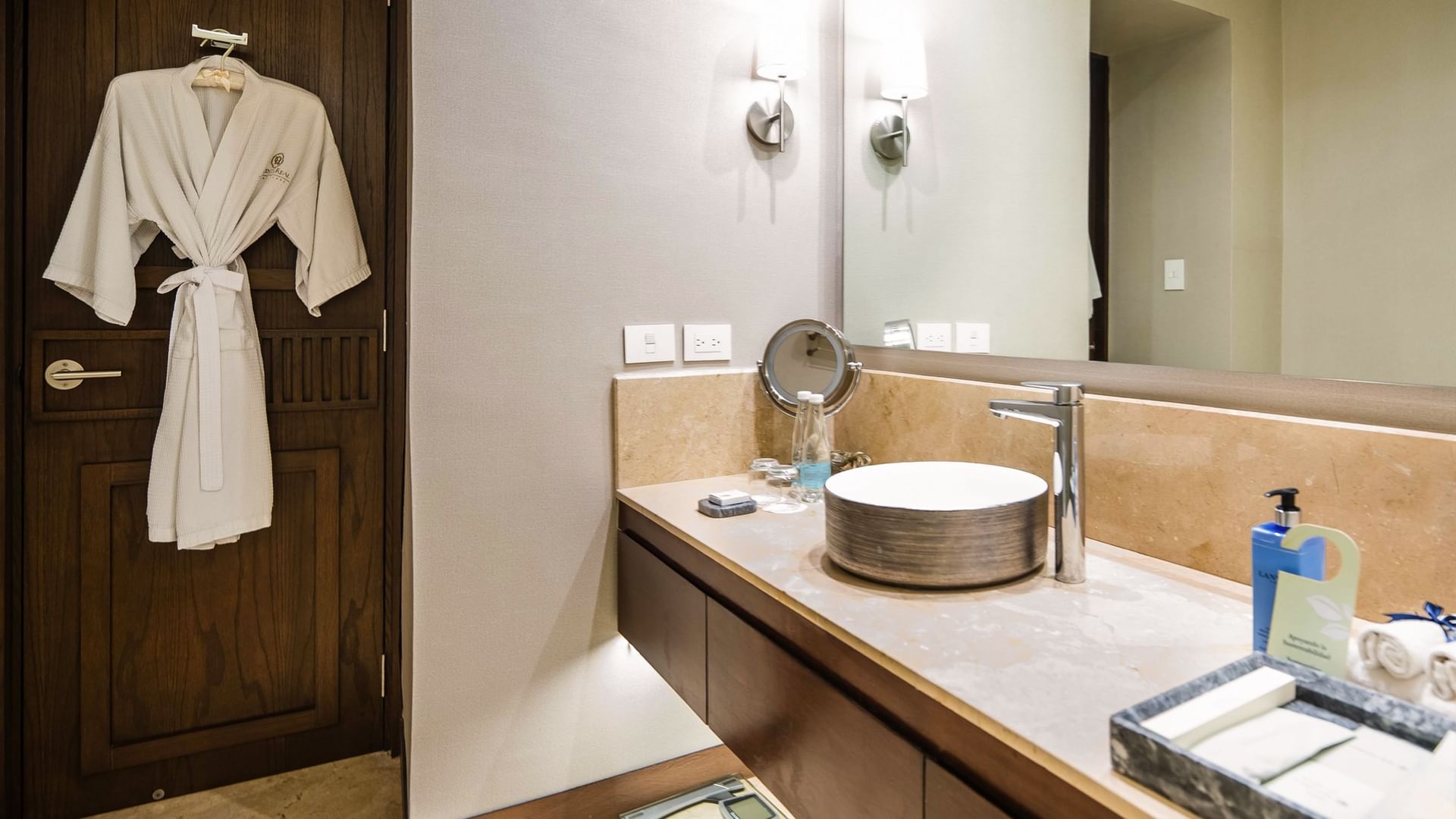 Elegant bathroom with bathrobe at door and sink with amenities at Quinta Real Puebla in Heroica Puebla de Zaragoza.