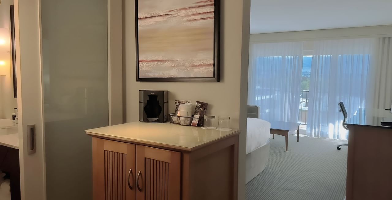 Hotel suite with bed, coffee machine, coffee, and work desk