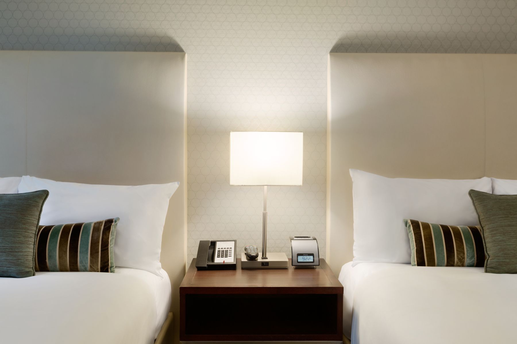 Night stand and lamp in-between two beds in hotel room