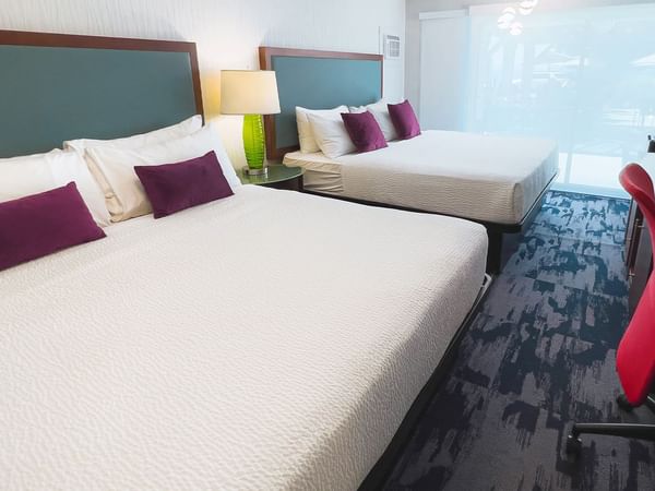 Guest room with two king beds, large desk, tv, patio doors, chair