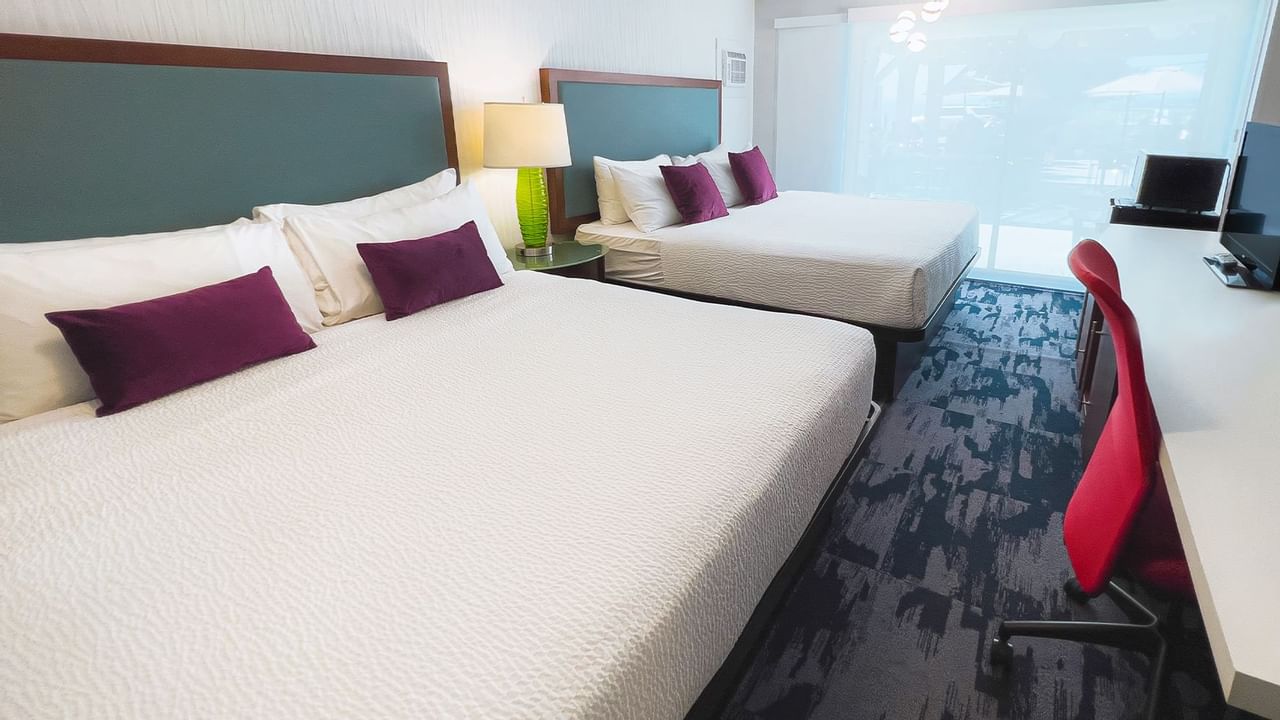 Guest room with two king beds, large desk, tv, patio doors, chair