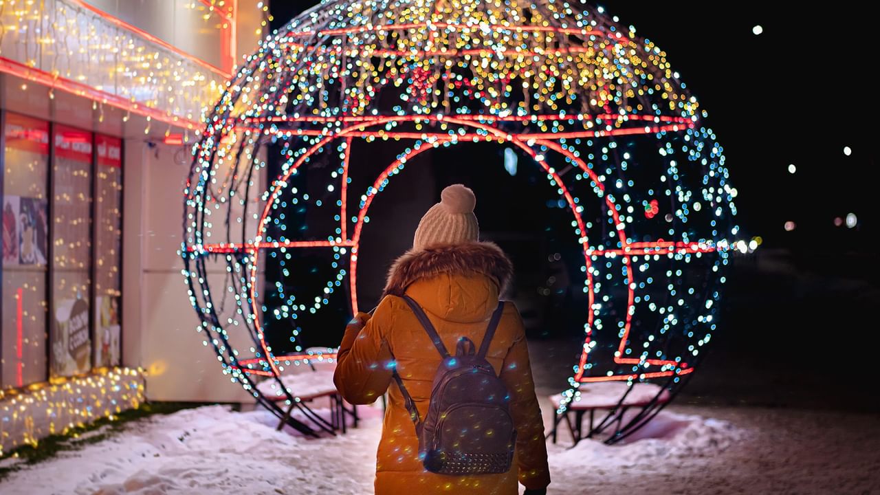 A woman stands before a large illuminated globe.