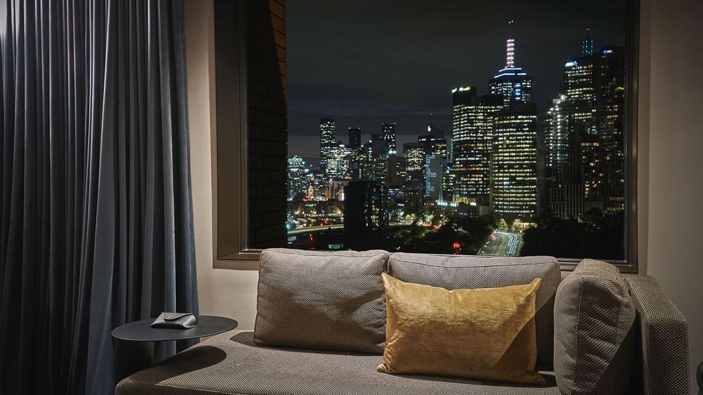 Superior Suite with sofa and panoramic nighttime city skyline view at Pullman East Melbourne