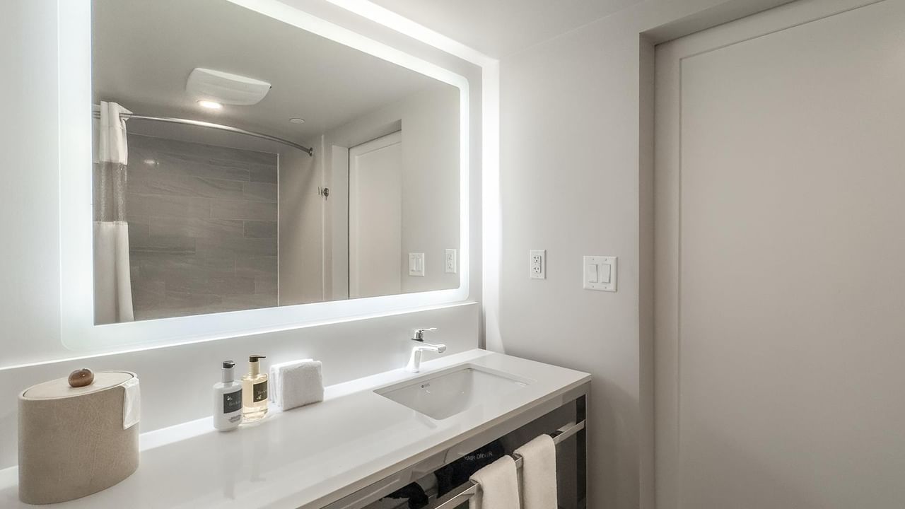 Modern bathroom with large mirror, sink, and towels.