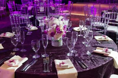 Wedding table setting with crystal glassware and rose centerpiece under purple lighting at Megapolis Hotel Panama