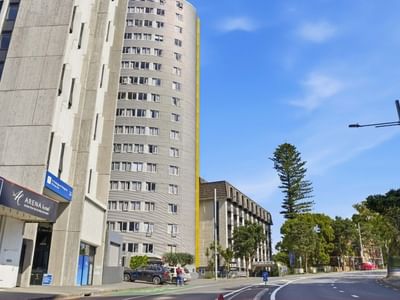 Street view of tall building with trees and cars in Auckland for Student Living.