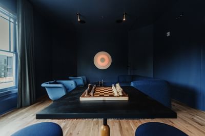 Club with a chessboard on a table, blue sofas, and abstract art at The Stonebreaker Hotel