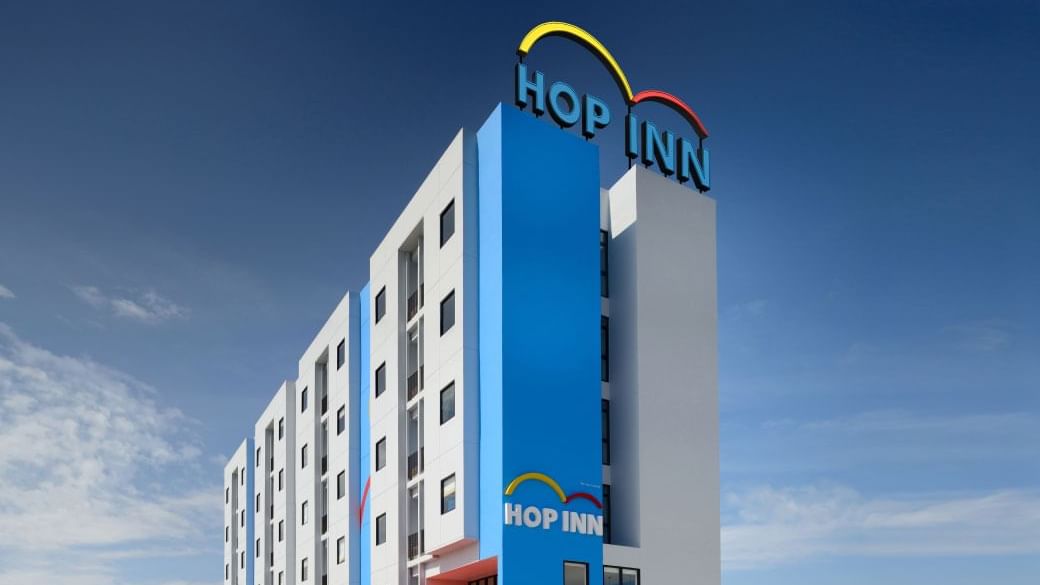 Hop Inn hotel building with bright blue and white facade standing under a clear blue sky