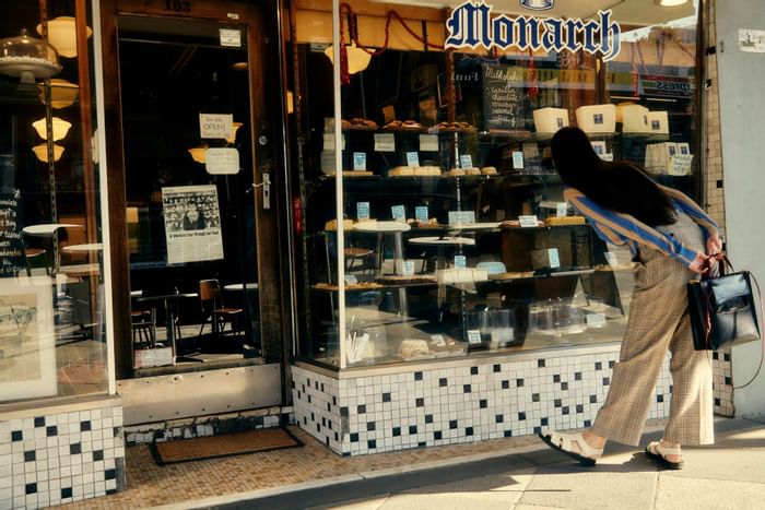 Girl looking through window of Monarchs cakes near The Kinson