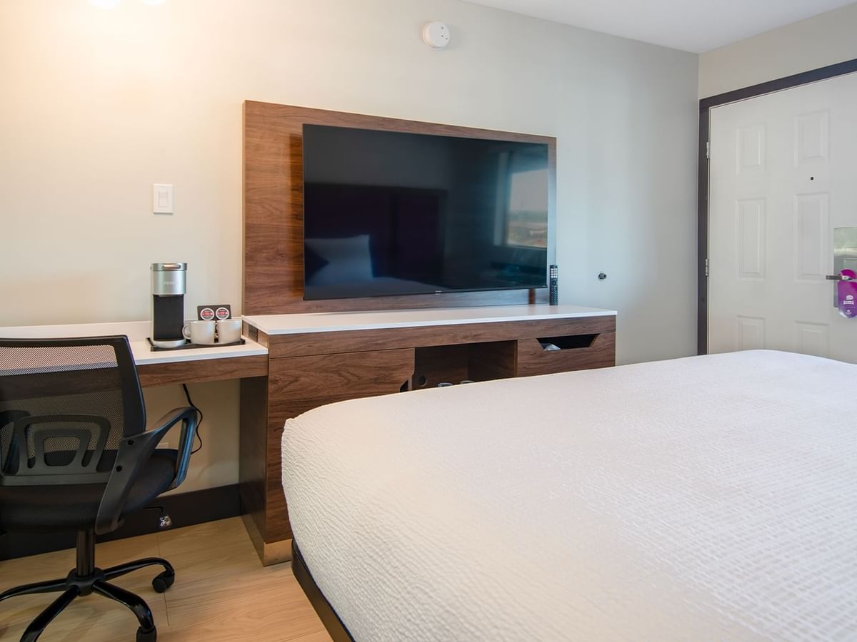 Hotel guestroom with king bed, work desk, flat screen TV, and coffee maker
