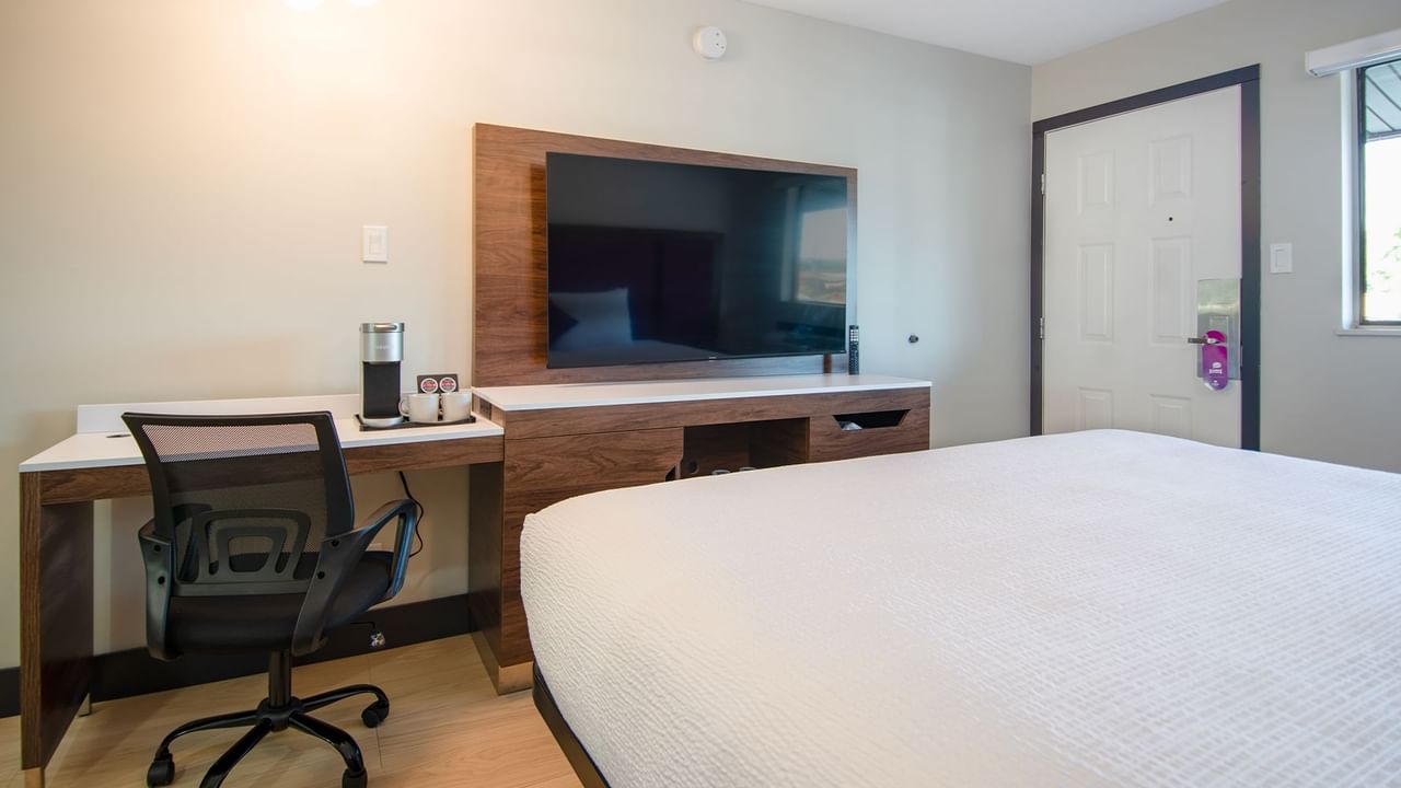 Hotel guestroom with king bed, work desk, flat screen TV, and coffee maker