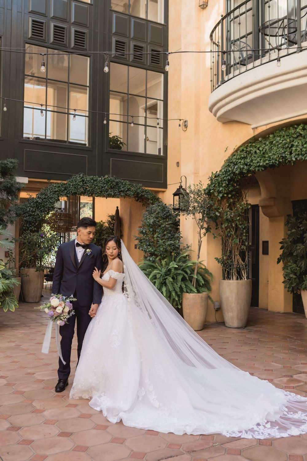 Beautiful bride and groom pose in the charming outdoor courtyard at El Prado Hotel