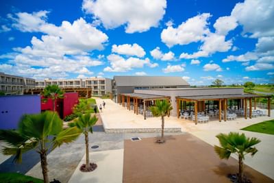 Distance view of The Hub Acunmeyda exterior with outdoor seating area surrounded by palm trees and lush greenery