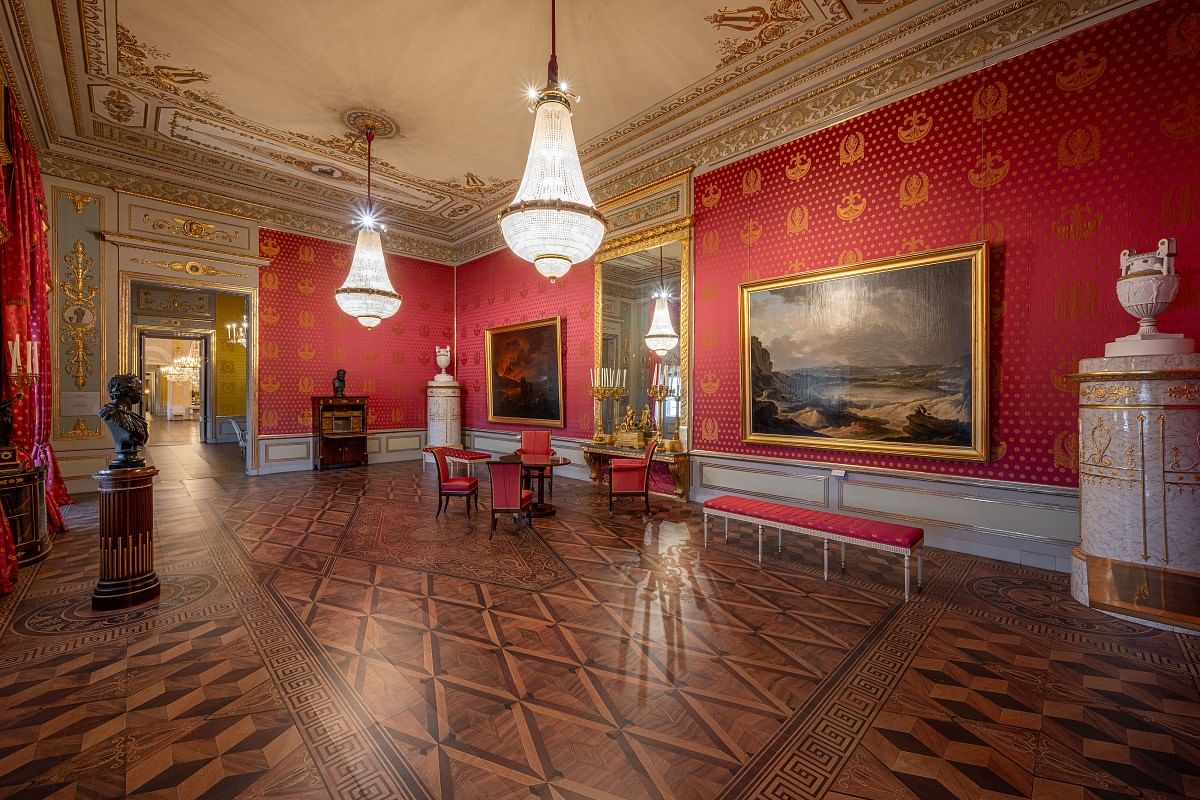 Historic state room at the Albertina in Vienna featuring red walls, chandeliers and classical Habsburg-era interior design.