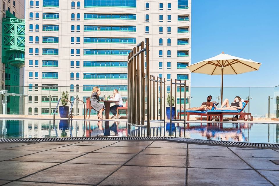 People relaxing by the rooftop pool area at Carlton Dubai Creek