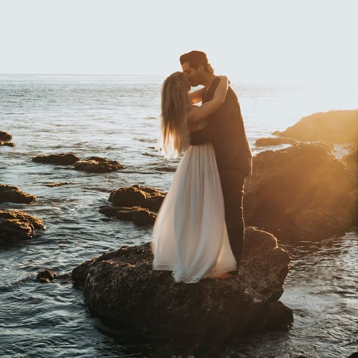Wedded couple kissing by the sea near Falkensteiner Hotels