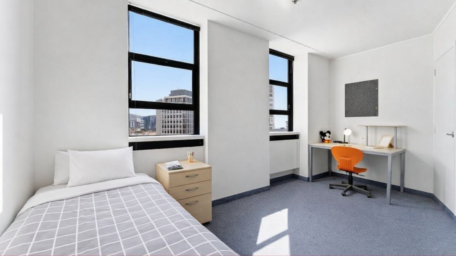 Tidy room with bed, desk, and two windows at UniLodge Stafford House.