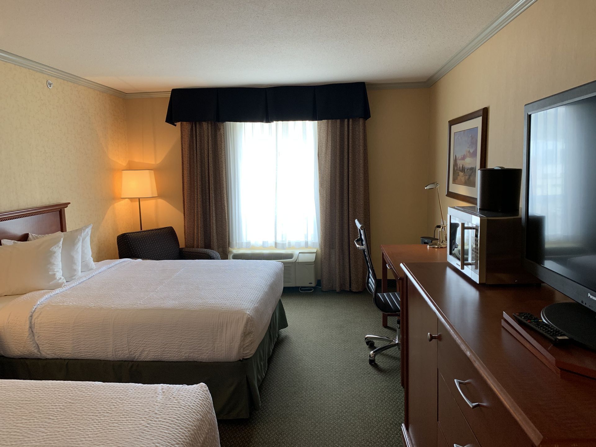 Workspace & TV facing the beds in Standard Two Queen at Merit Hotel & Suites